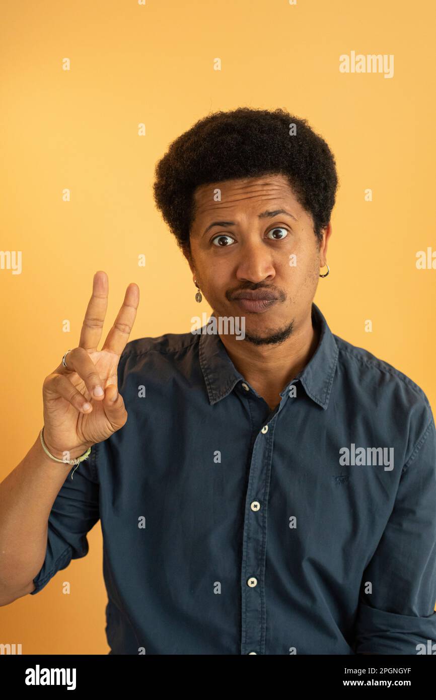 Homme montrant le signe de la paix geste sur fond jaune Banque D'Images