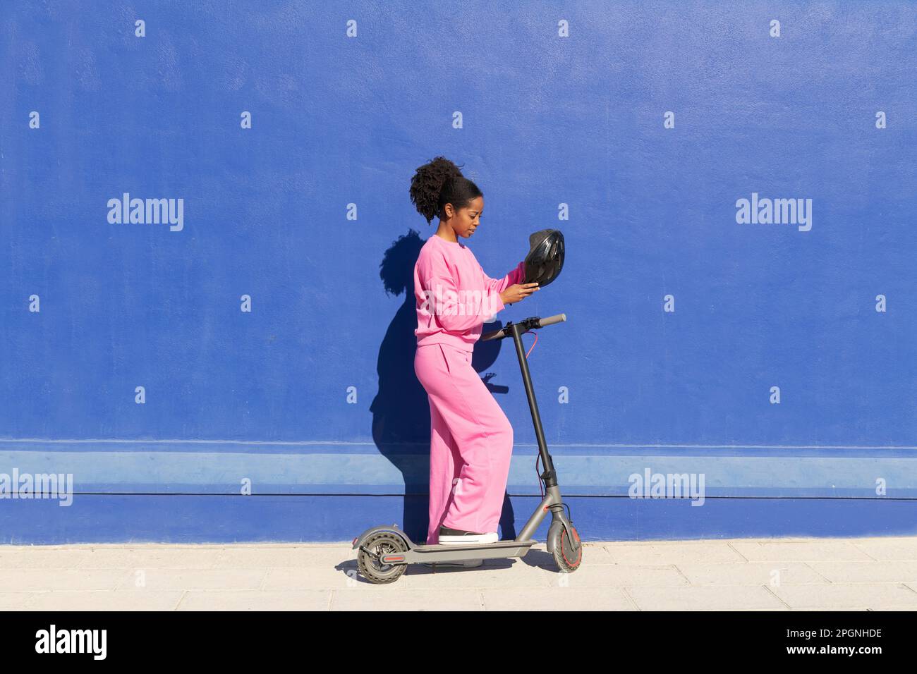 Femme portant un casque sur un scooter électrique sur une piste de marche Banque D'Images