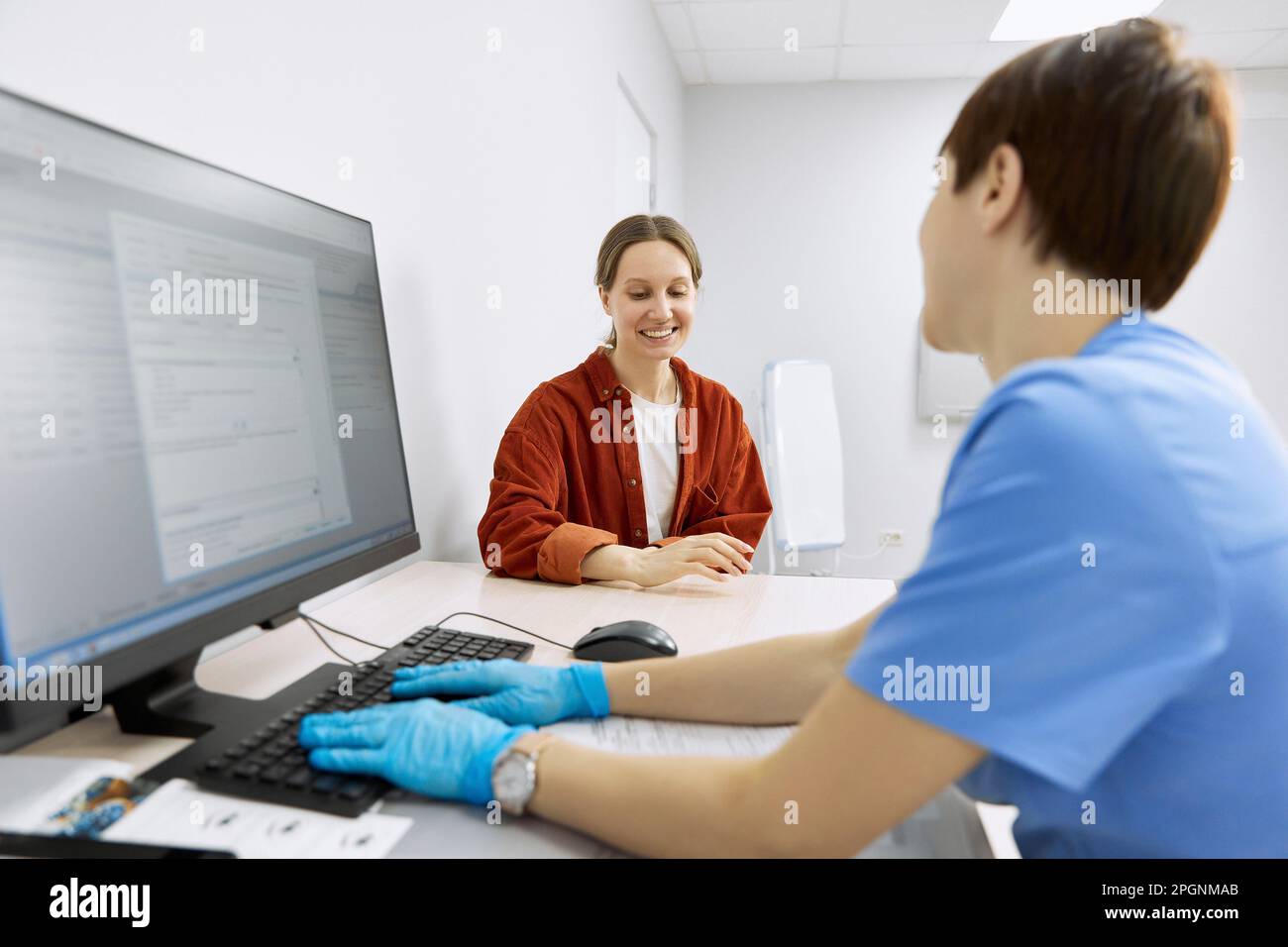 Patient souriant discutant avec un ophtalmologiste à la clinique Banque D'Images