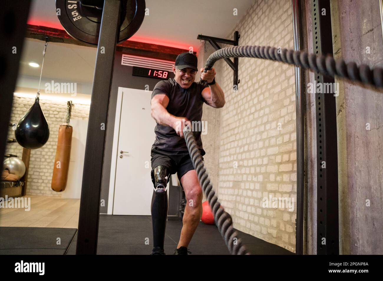 Homme mature avec une jambe prothétique faisant des cordes de combat en salle de gym Banque D'Images