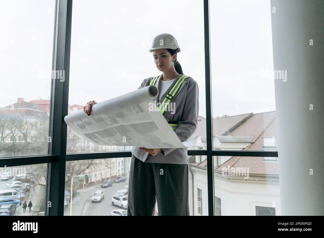 Architecte examinant le plan en face de la fenêtre au bureau Banque D'Images