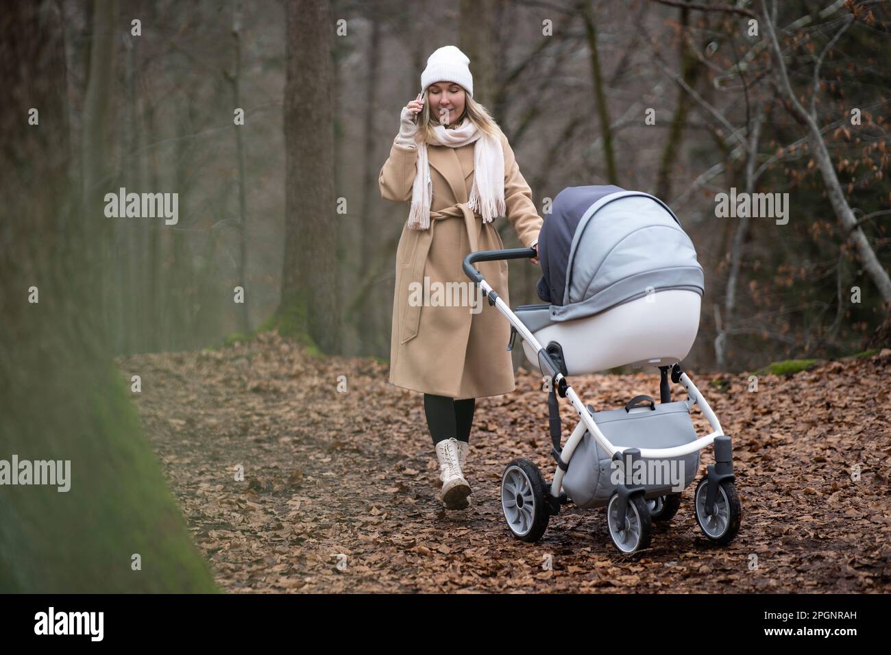 Femme avec poussette de bébé parlant sur un smartphone en forêt Banque D'Images