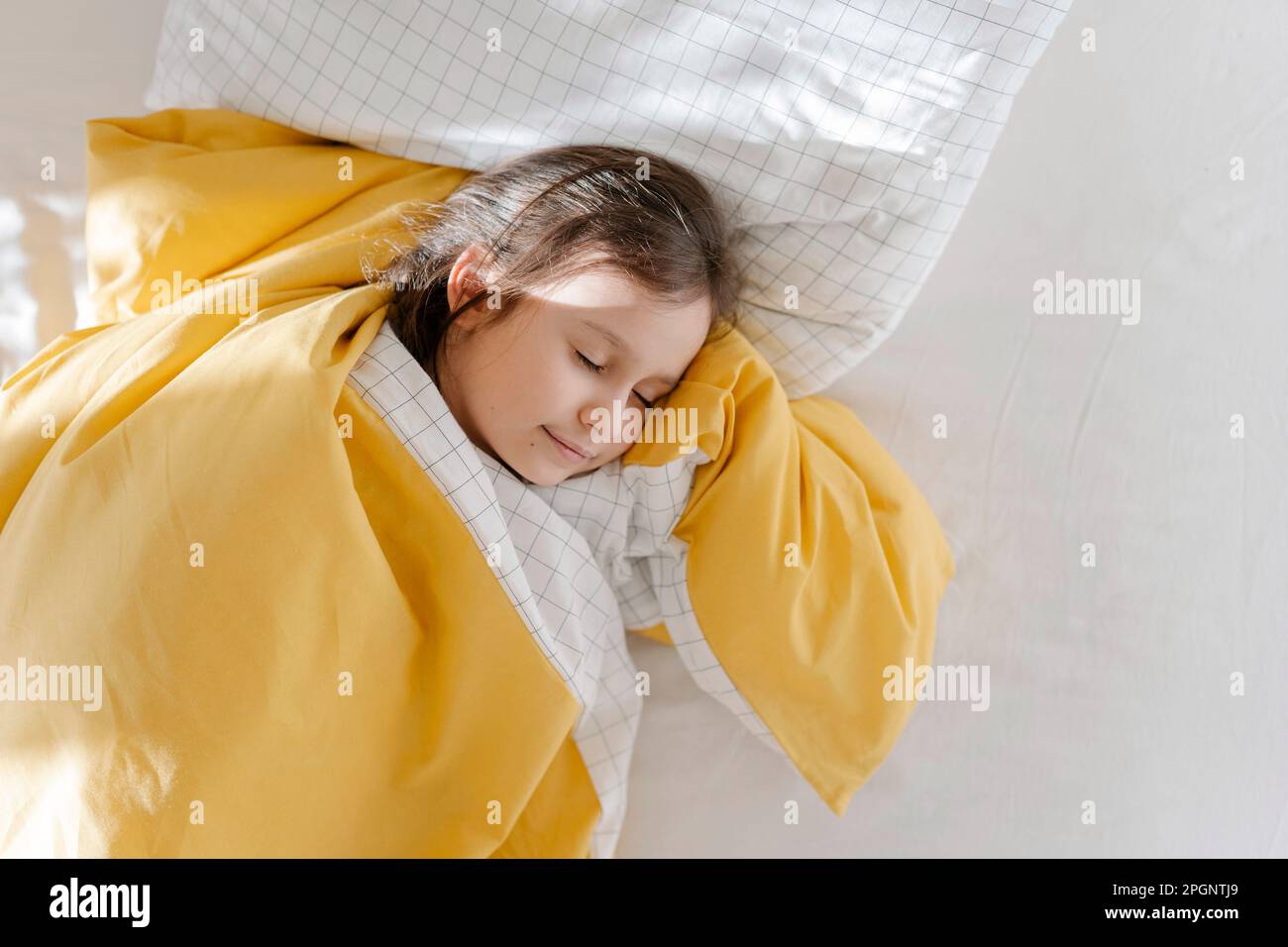 Fille dormant avec couverture sur le lit Banque D'Images