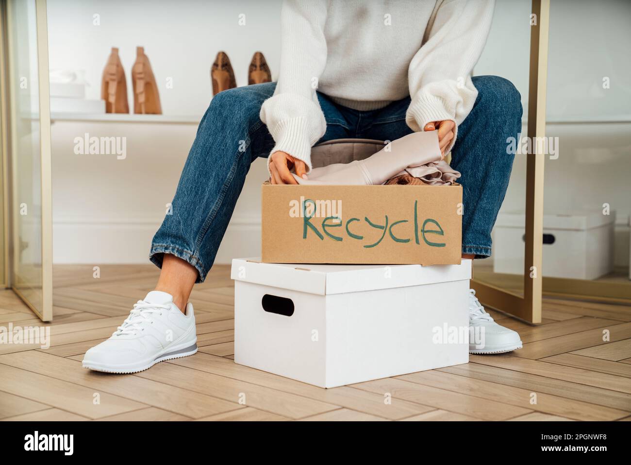 Jeune femme emballage des boîtes de recyclage des vêtements à la maison Banque D'Images