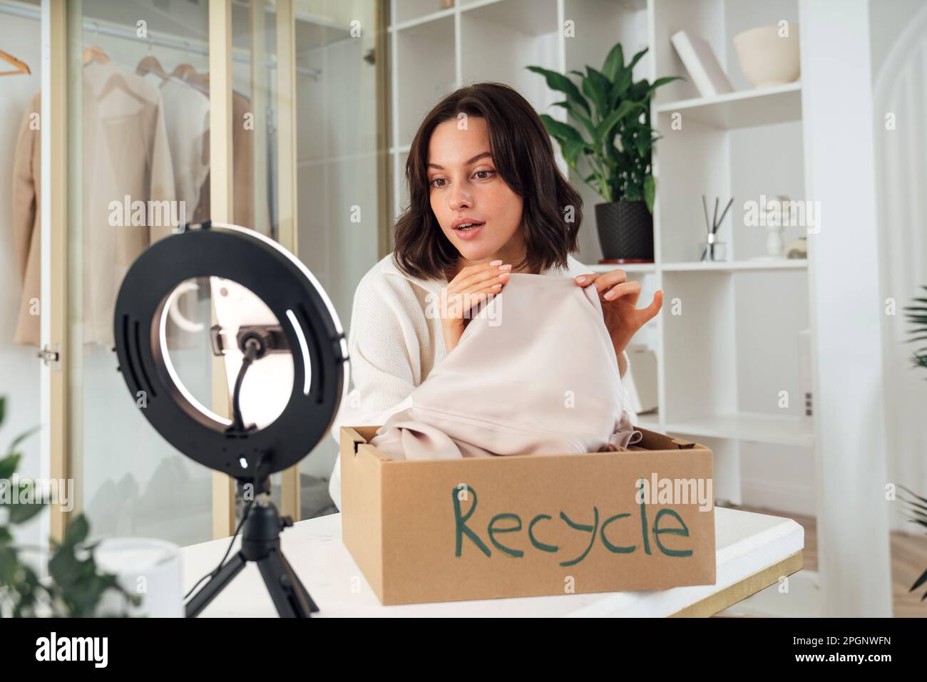 Influenceur montrant des vêtements à recycler par le biais d'un smartphone à la maison Banque D'Images