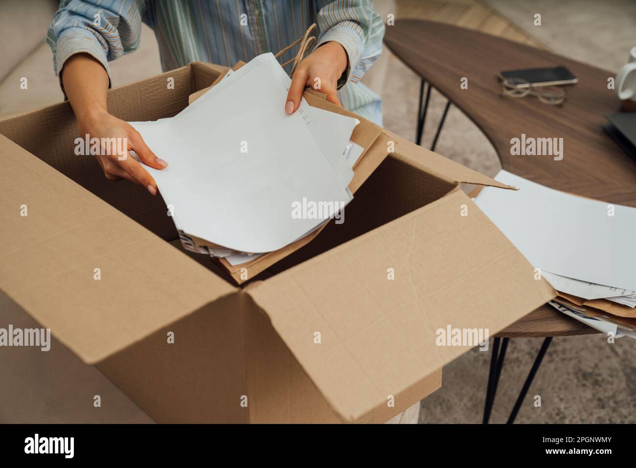Mains de femme recyclant les papiers dans la boîte à la maison Banque D'Images