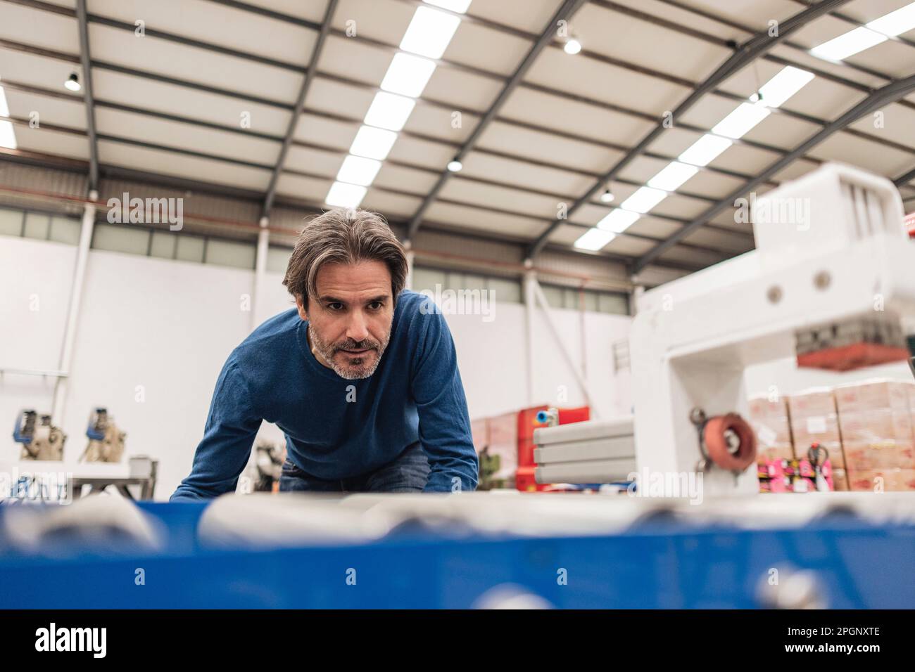 Un ingénieur expérimenté examine le tapis transporteur en usine Banque D'Images