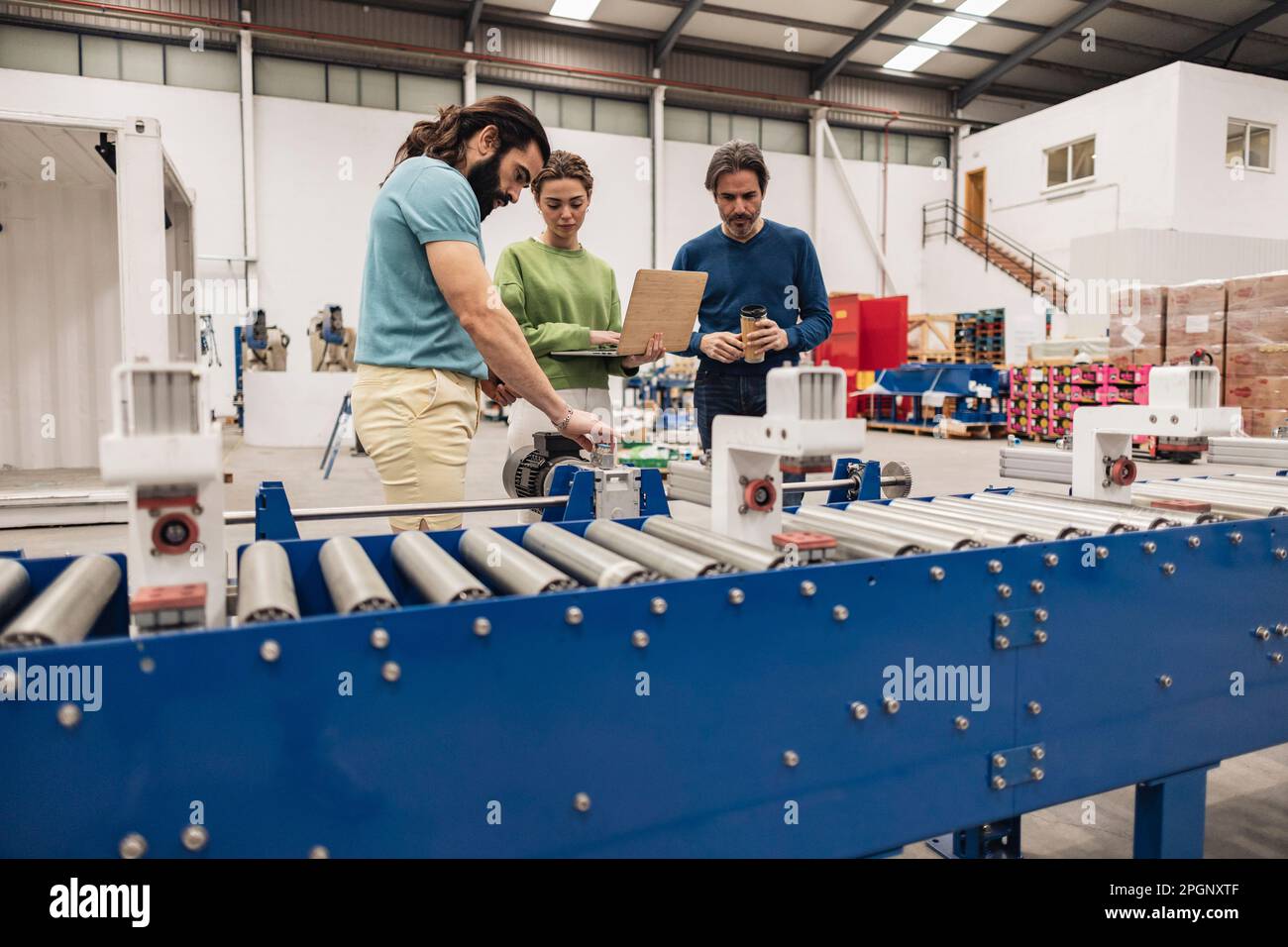 Les ingénieurs examinent en usine les pièces de la machine se trouvant sur le tapis convoyeur Banque D'Images
