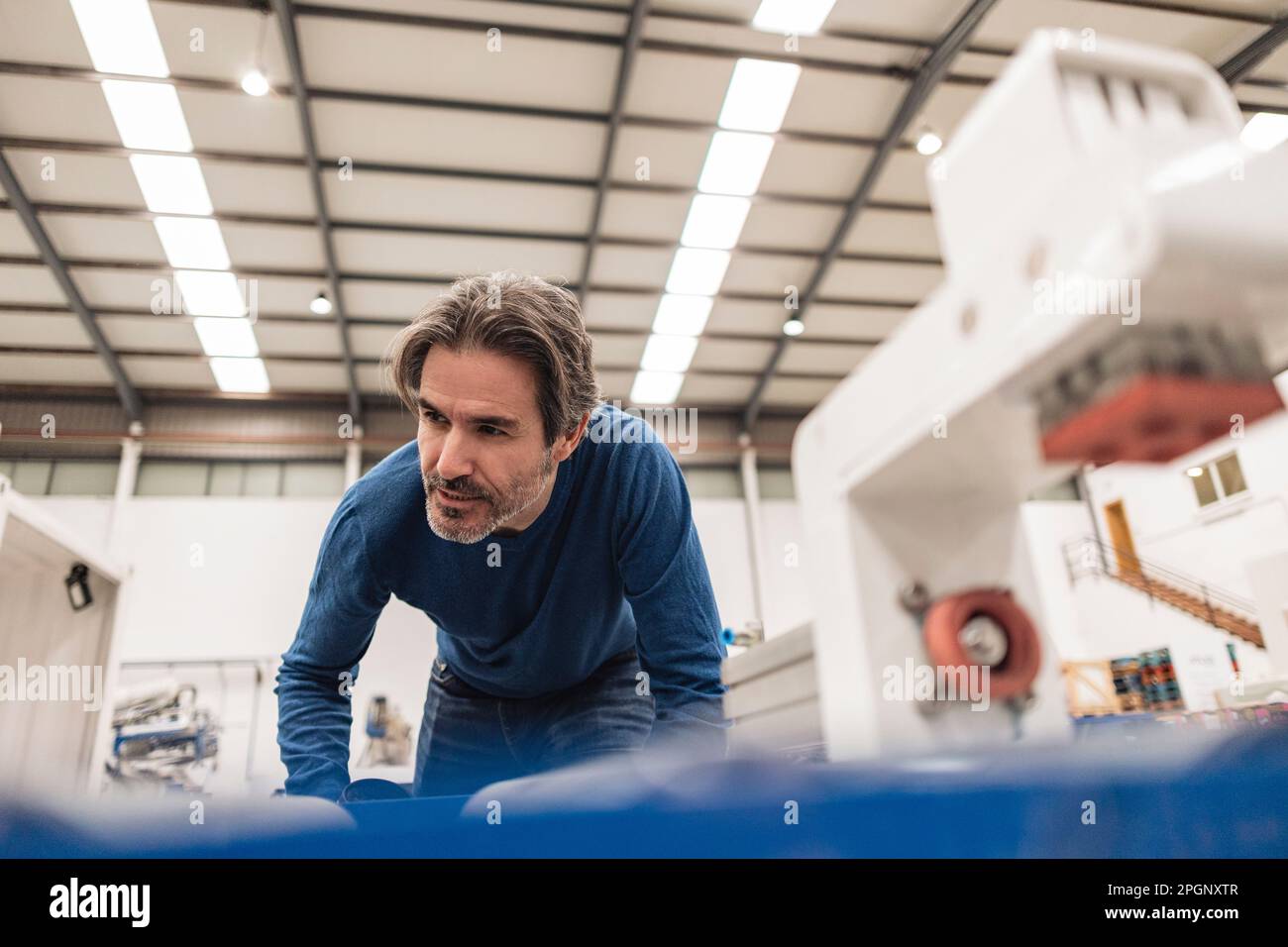 Un ingénieur expérimenté examine le tapis transporteur dans une usine de robotique Banque D'Images