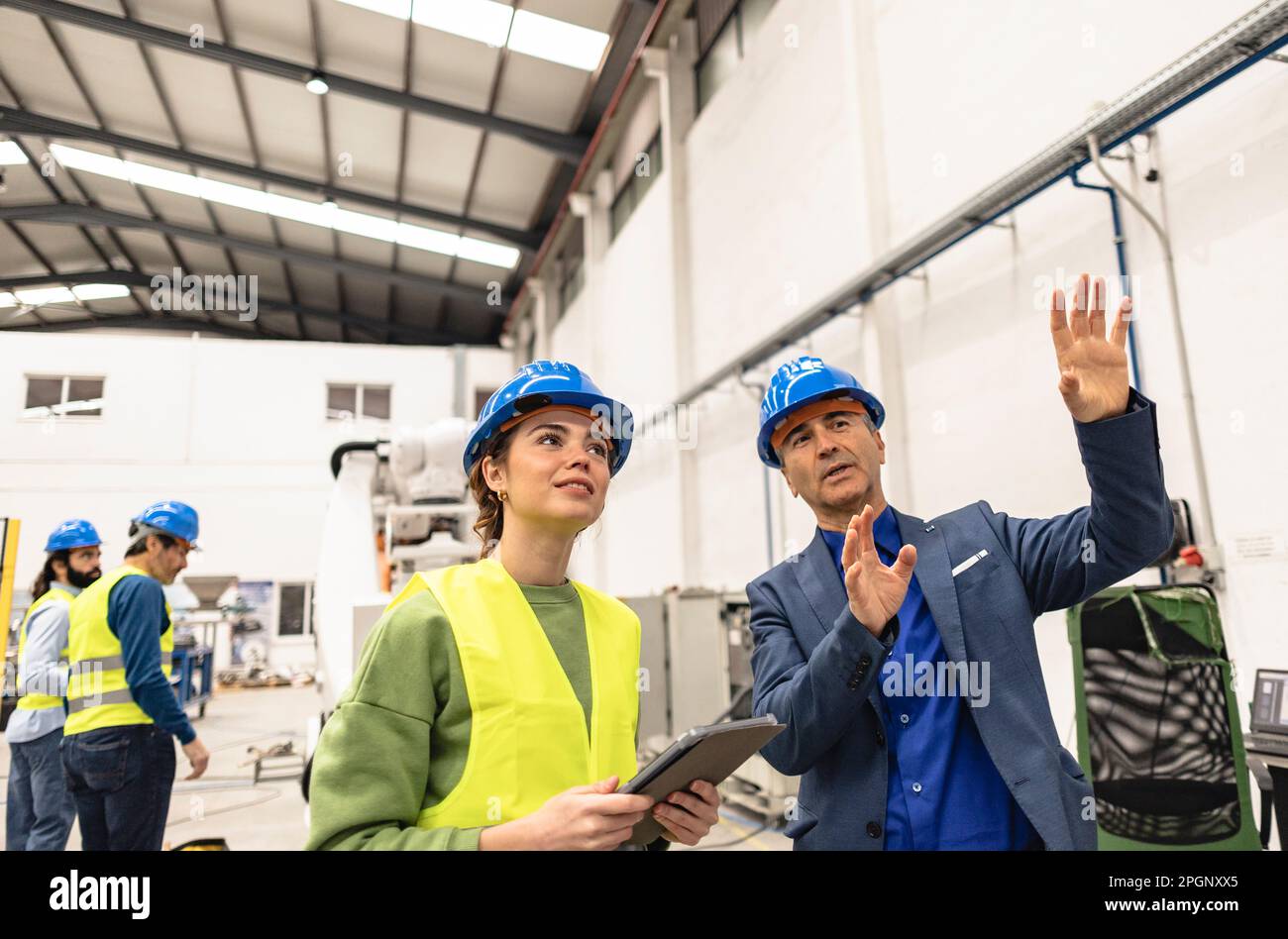 Un ingénieur souriant explique son collègue en usine Banque D'Images