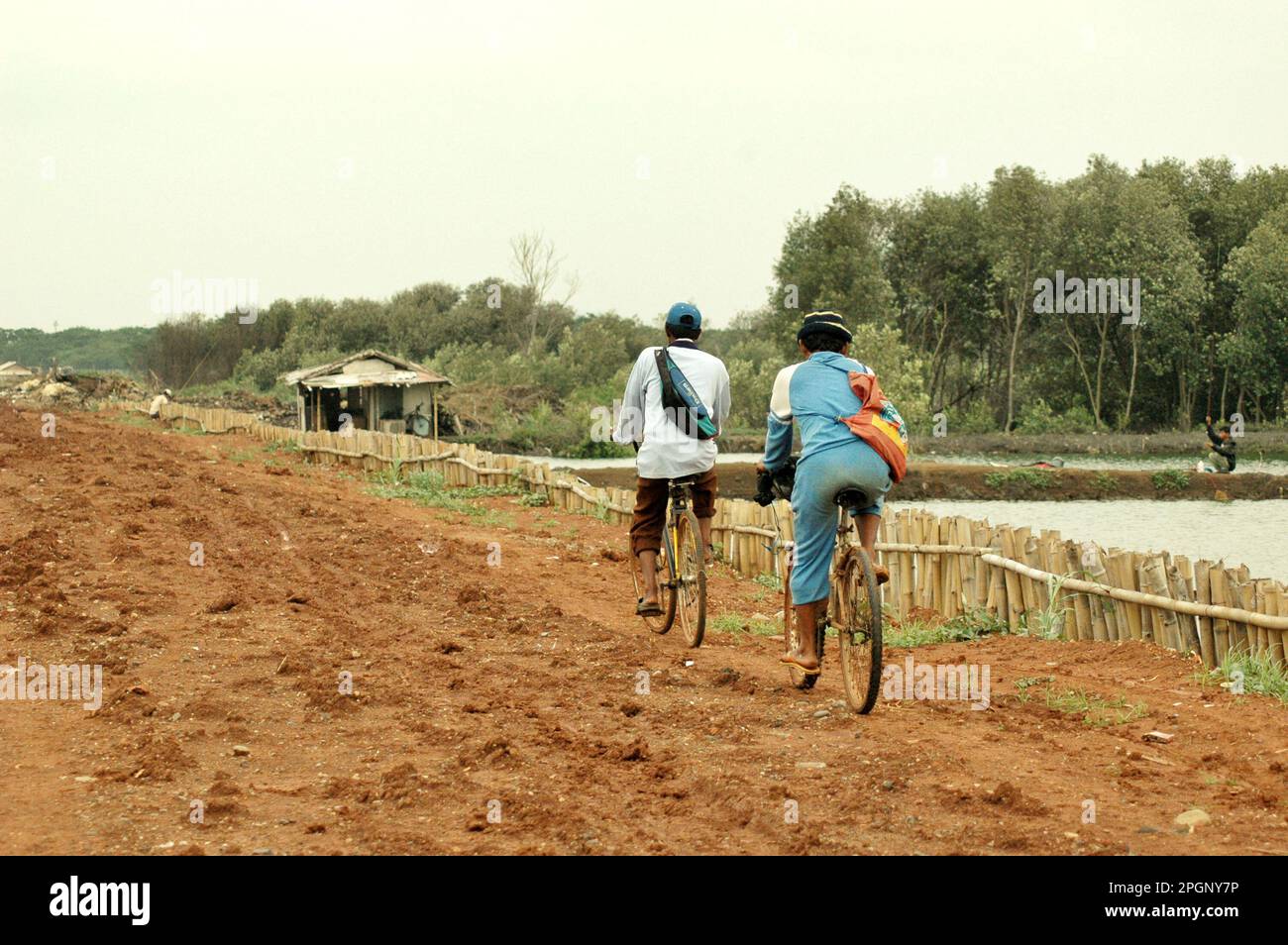 Les travailleurs voyagent sur une route de terre à travers une zone côtière qui est affectée par le développement urbain à Jakarta, en Indonésie. Banque D'Images