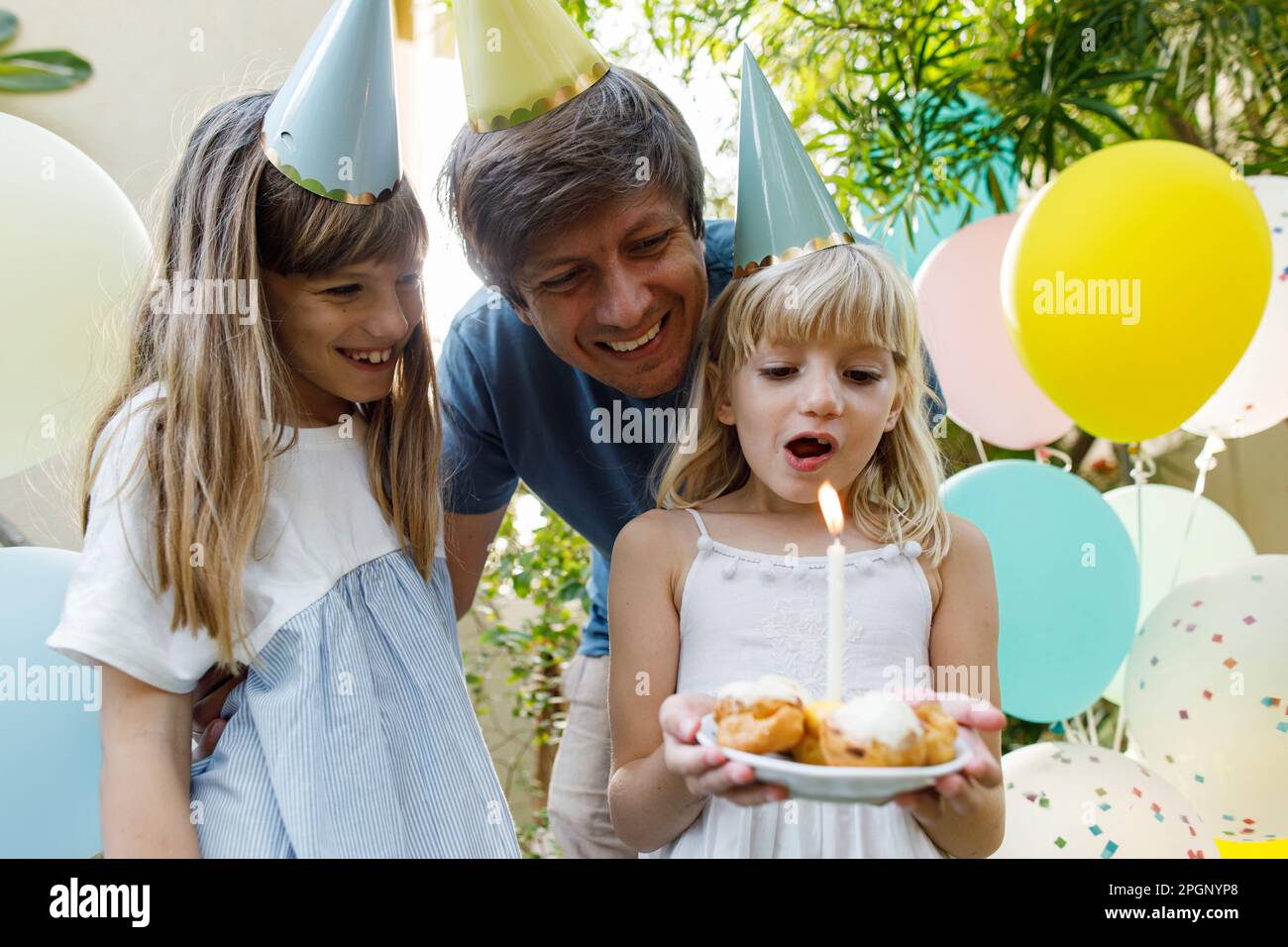 Filles heureuses avec un père célébrant son anniversaire dans le jardin Banque D'Images