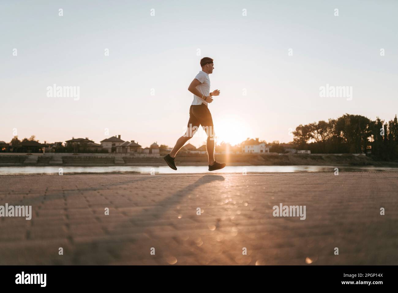 Jeune homme qui court sur une piste de jogging au coucher du soleil Banque D'Images