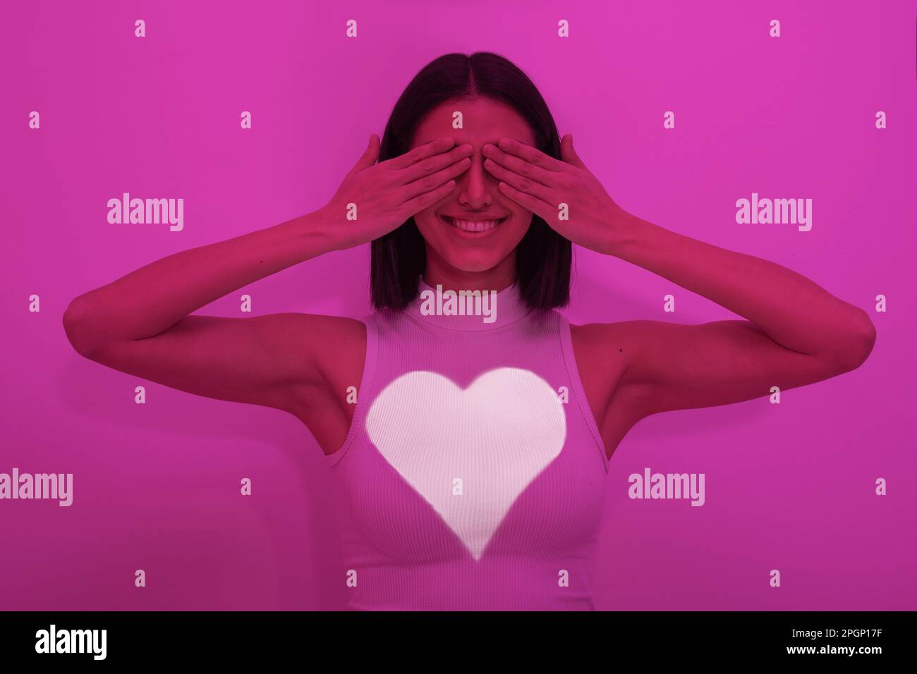 Bonne femme couvrant les yeux sur fond rose Banque D'Images