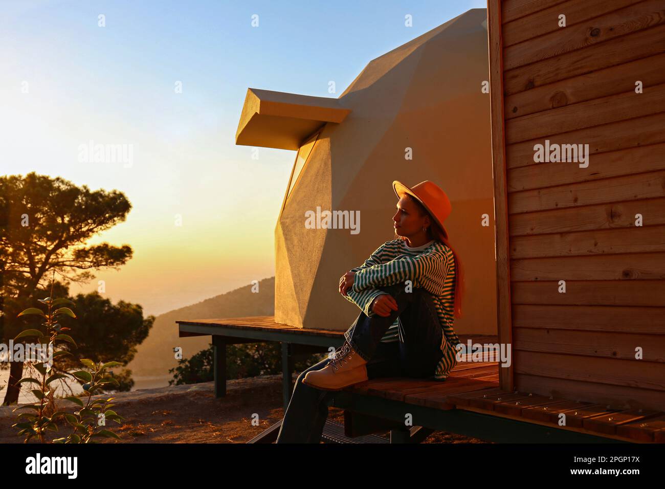 Jeune femme assise près d'un bâtiment durable au coucher du soleil Banque D'Images