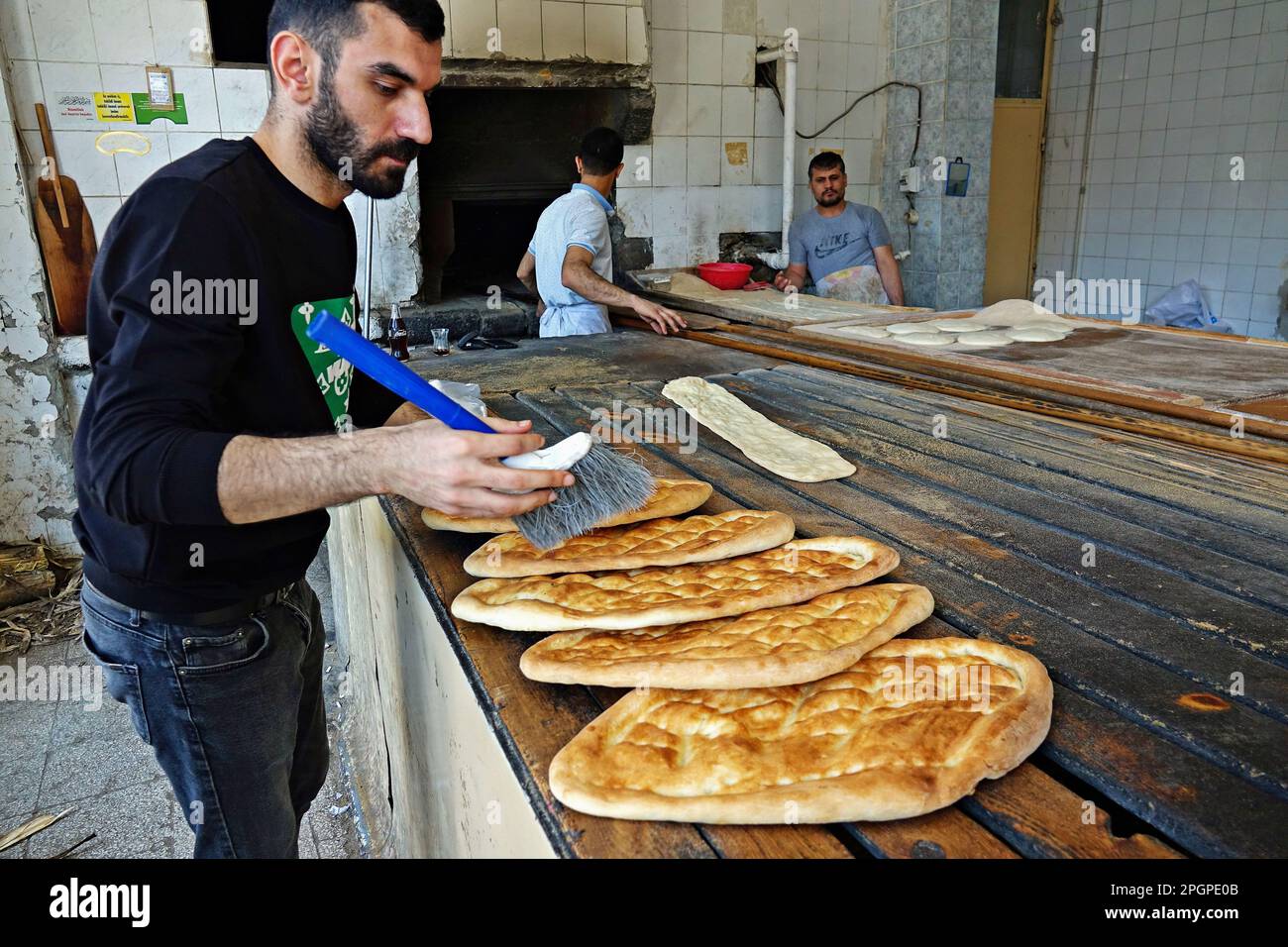 Ferhat Erzem est vu nettoyer les pains ménagers qui sortent du four avec  une brosse. La tradition de cuisson des beignets avant le mois du Ramadan  et d'Eid al-Fitr se poursuit dans