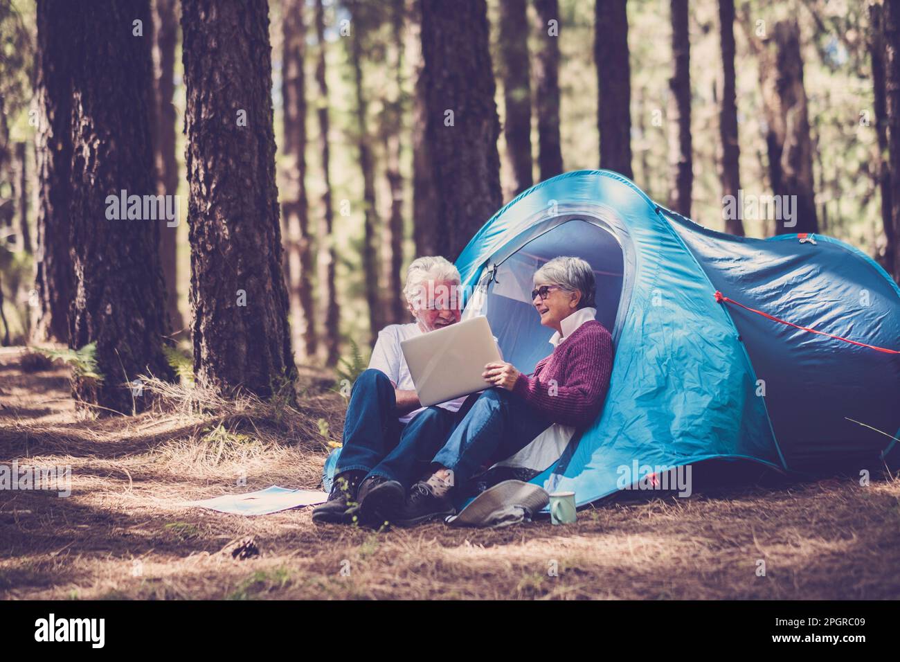 Couple de personnes âgées d'âge mûr aiment la nature activités de loisirs en plein air assis à l'extérieur d'une tente dans la forêt. Joyeux jeune homme et femme âgé de plus en plus Banque D'Images