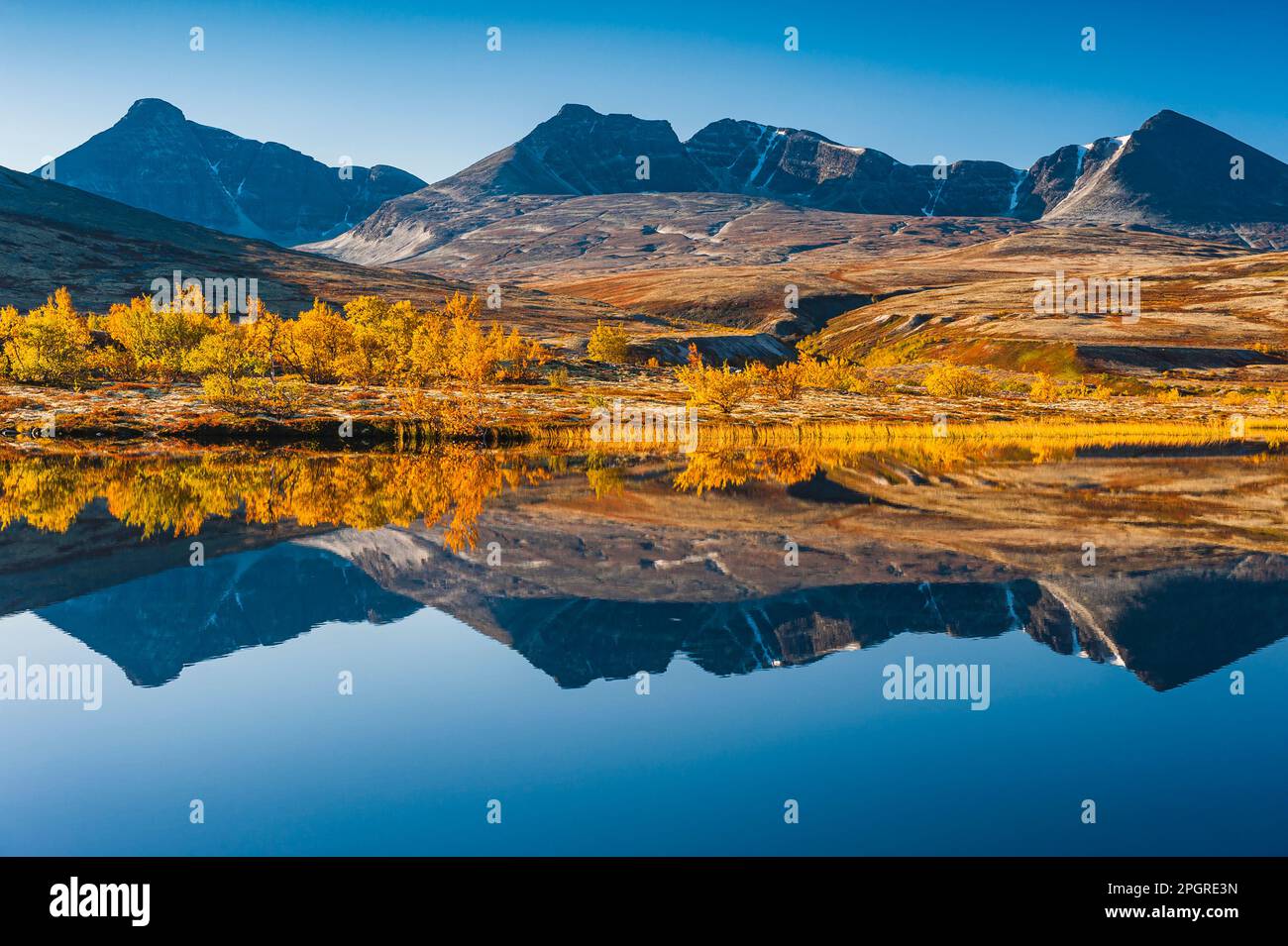 Le reflet d'une chaîne de montagnes tranquille sur la surface vivivivile d'un lac norvégien peint un paysage automnal plein de beauté et de tranquillité. Banque D'Images
