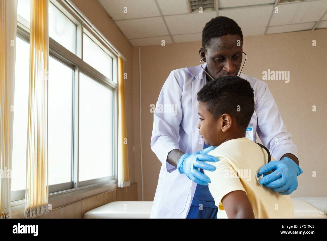 médecin pédiatre afro-américain utilisant le stéthoscope pour examiner un garçon de la maladie en cabinet à l'hôpital. médical et sain. Banque D'Images