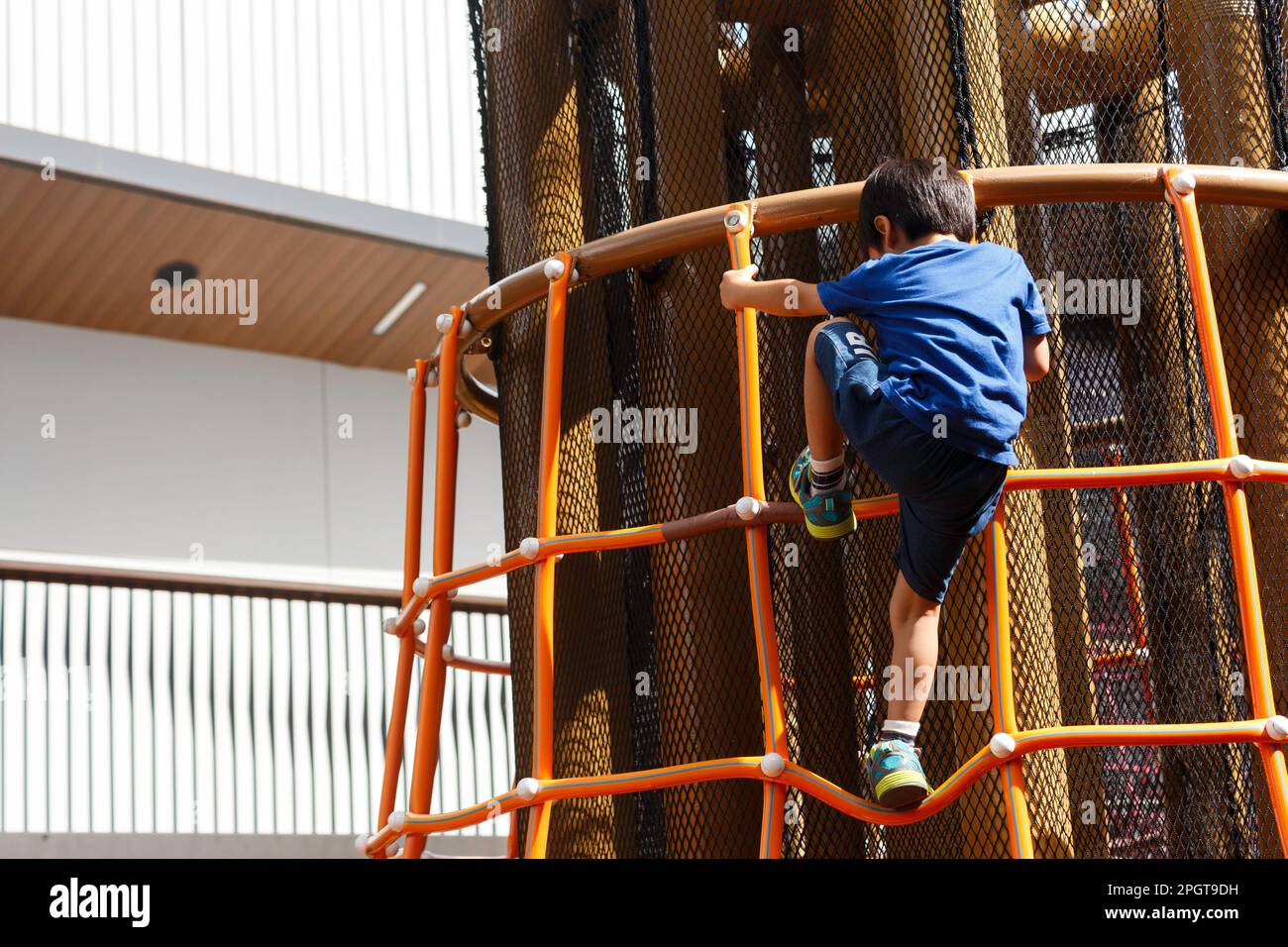 bon garçon asiatique sur le terrain de jeu. le week-end, un garçon monte sur l'échelle dans l'aire de jeux publique du parc municipal. Banque D'Images