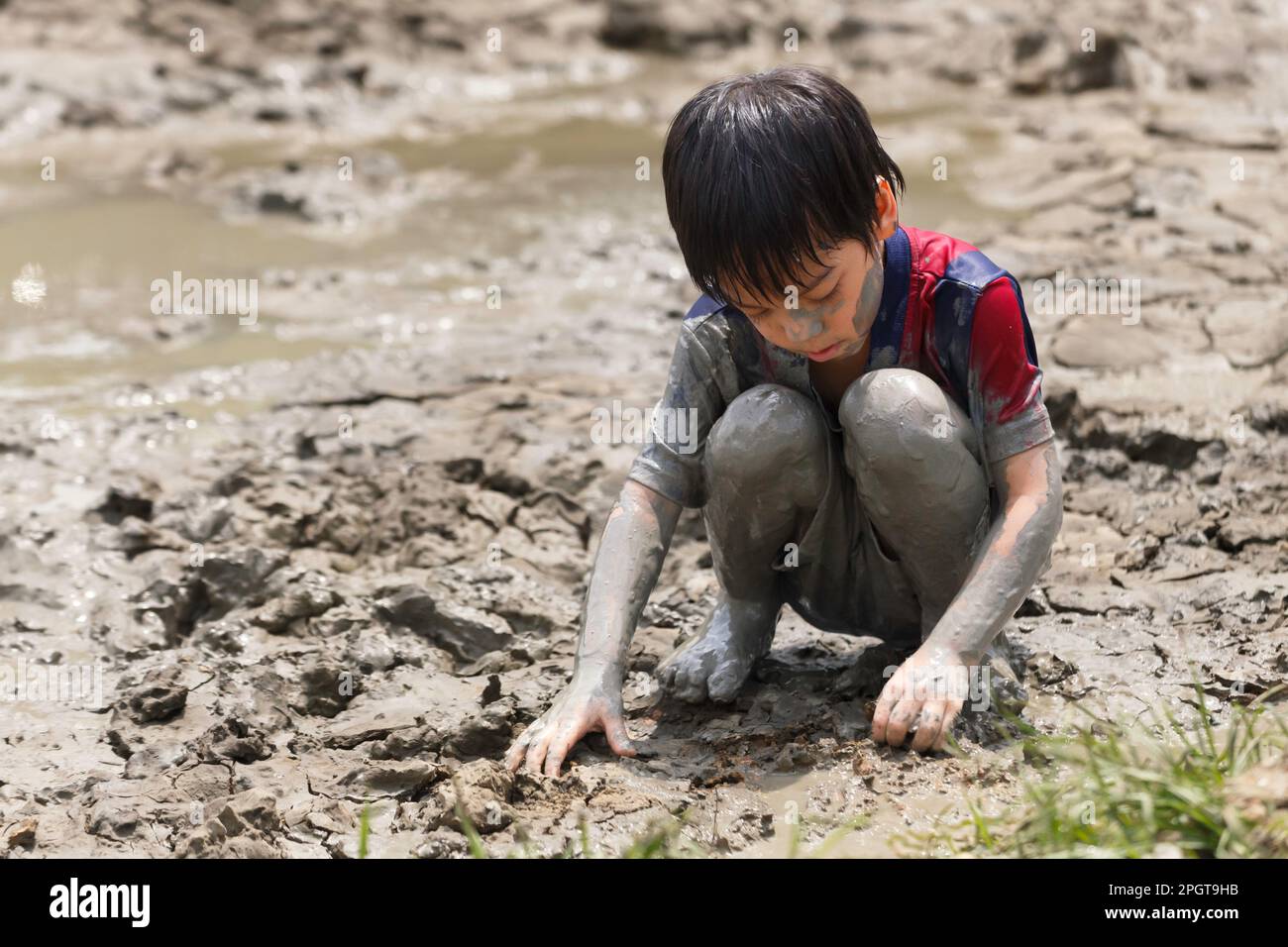mignon petit garçon asiatique heureux appréciant de jouer dans la boue à l'aire de jeux. l'apprentissage des enfants dans la nature à l'école montessori. nature et concept d'éducation. Banque D'Images