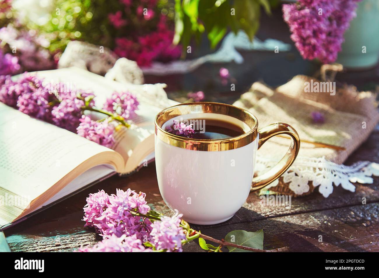 Style de vie typique de chalet - pause café avec une tasse de café, livre et fleurs lilas. Concept détente et loisirs. Banque D'Images