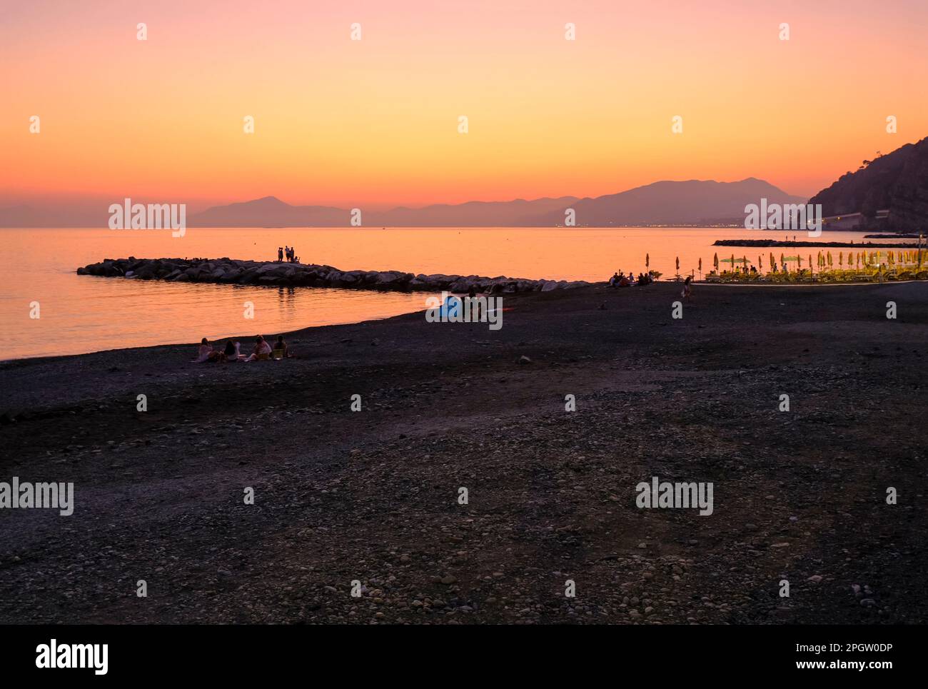 coucher de soleil sur la plage avec chaises longues jaunes sur la mer et l'horizon et collines avec les hôtels. Sestri Levante, Ligurie, Italie Banque D'Images