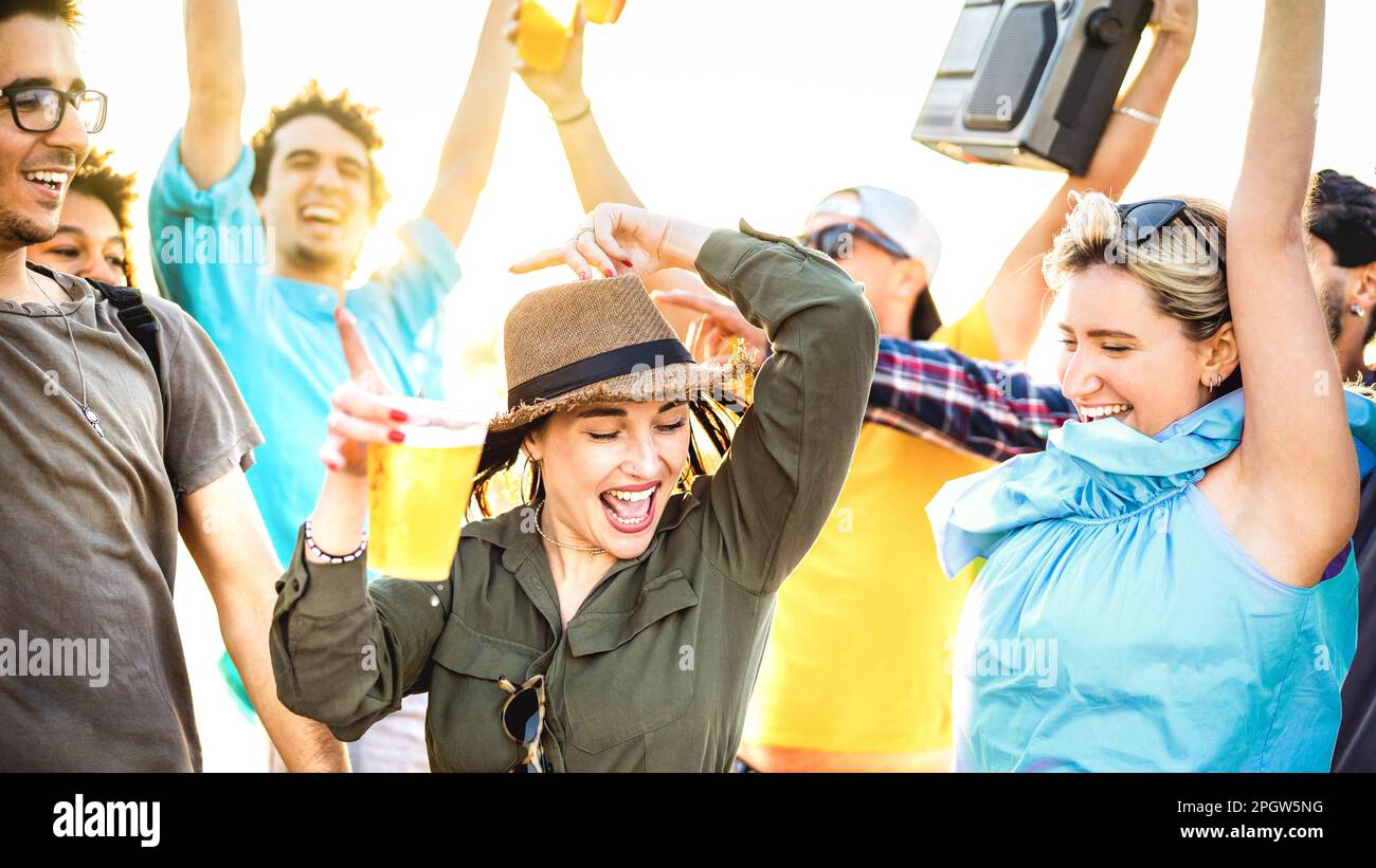 Des amis heureux dansant au coucher du soleil pendant les vacances de fête - concept de style de vie d'été avec les jeunes s'amuser ensemble au festival de vacances de printemps Banque D'Images