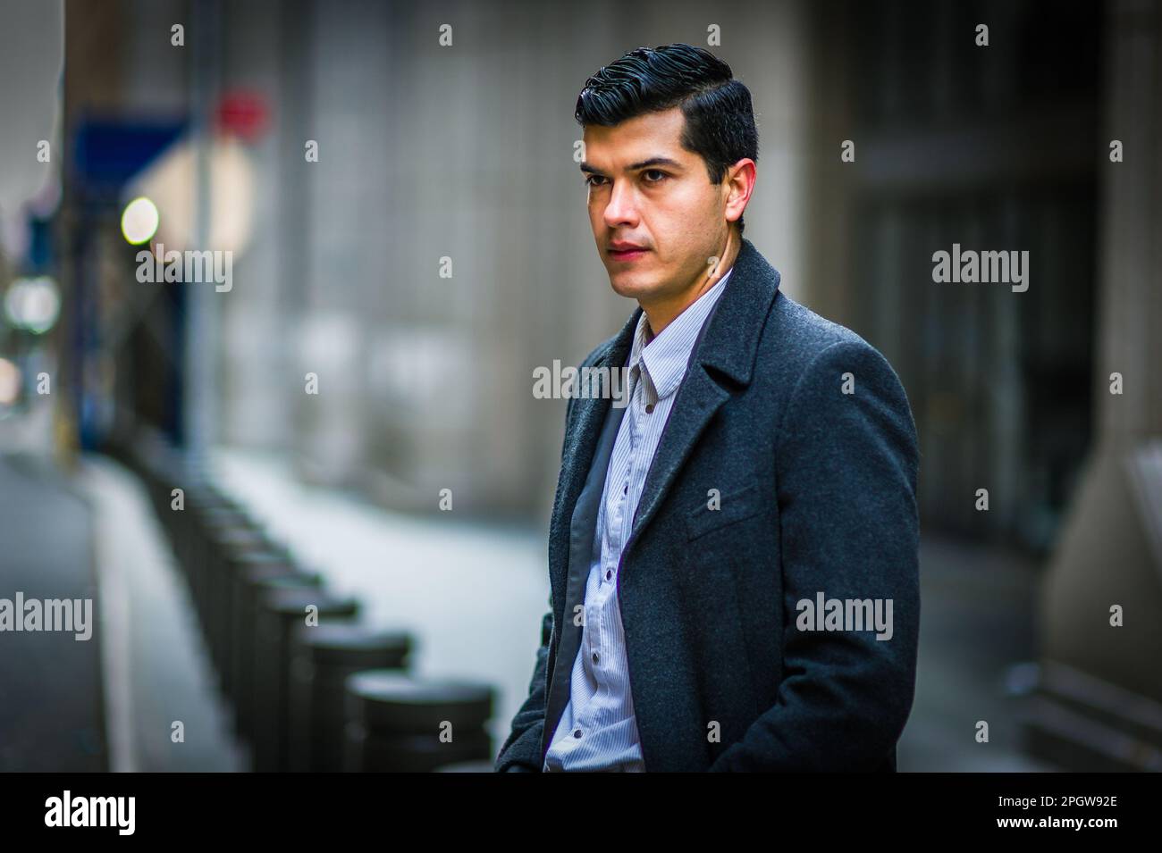 Jeune homme portant un manteau noir, assis dans la vieille rue de New York en hiver, pensant. Banque D'Images