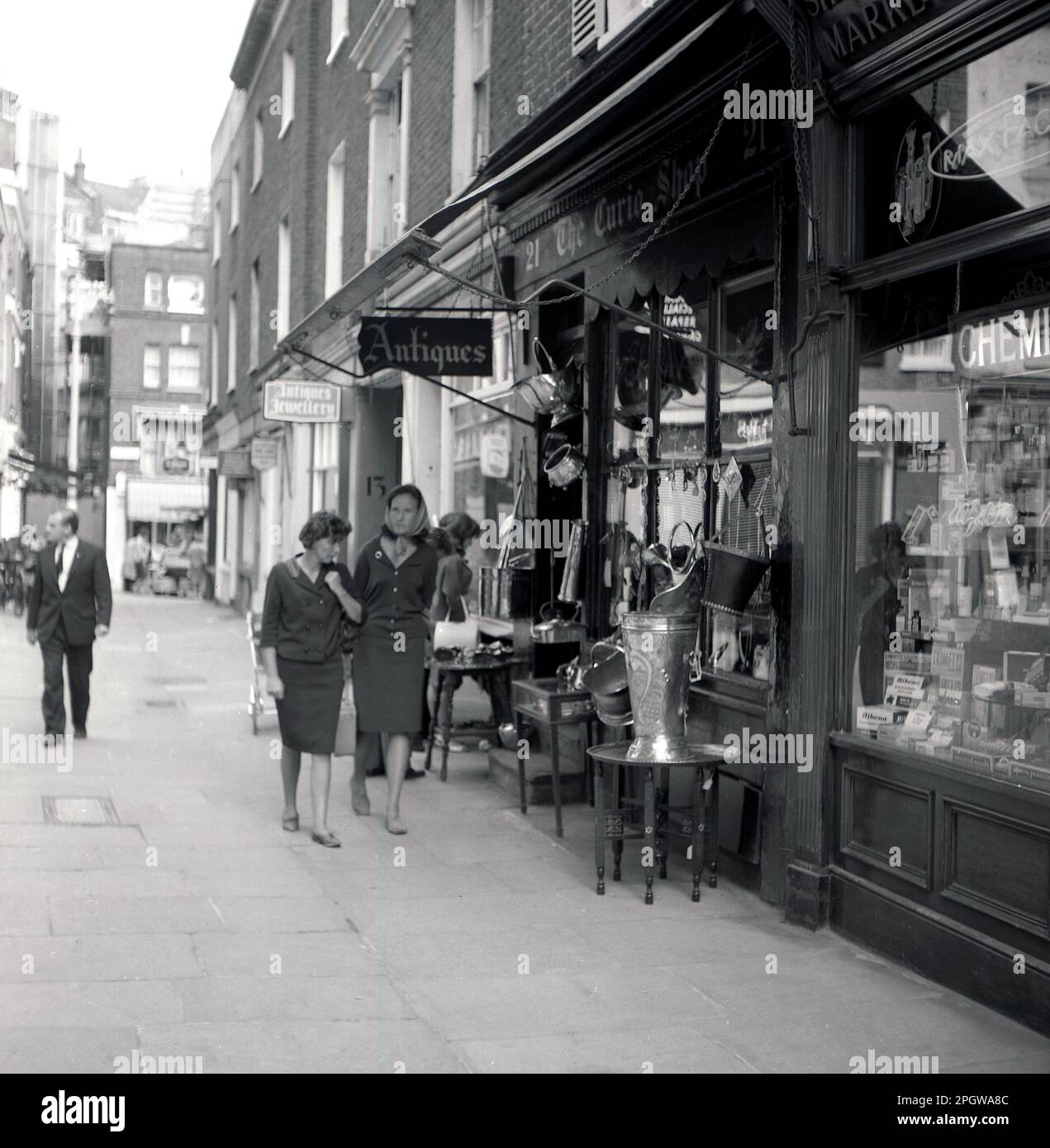 1960s, historique, deux dames se promenant devant un magasin d'antiquités, le Curio Shop, dans un passage latéral, Londres, Angleterre, Royaume-Uni. Banque D'Images