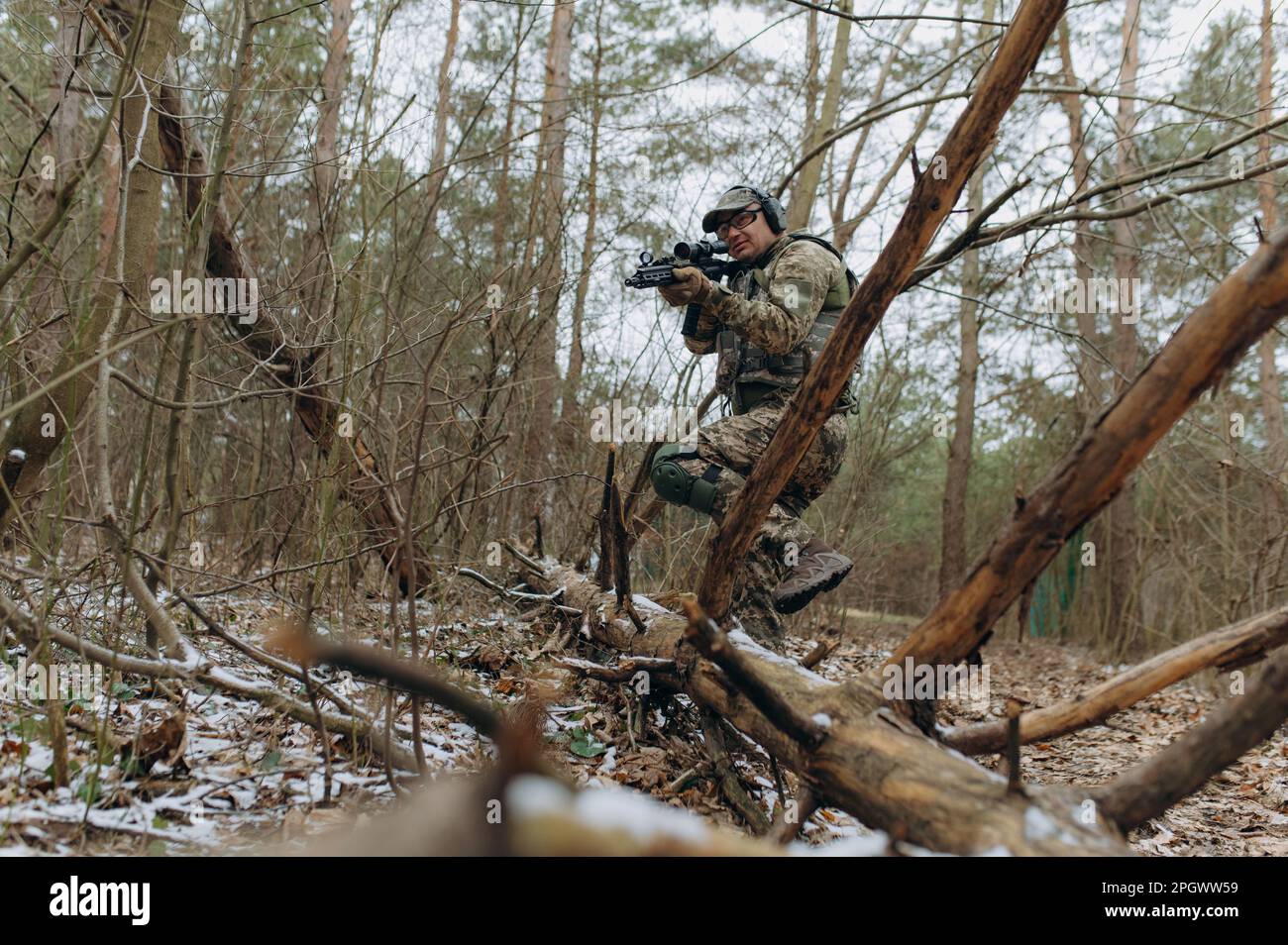 militaire en uniforme de camouflage sur les branches d'arbre, dans une embuscade avec une arme, une mitrailleuse. actions militaires un soldat dans la forêt. Banque D'Images