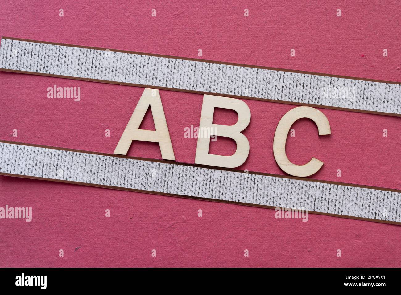 Affiche avec les lettres ABC en bois sur papier rose rugueux Banque D'Images