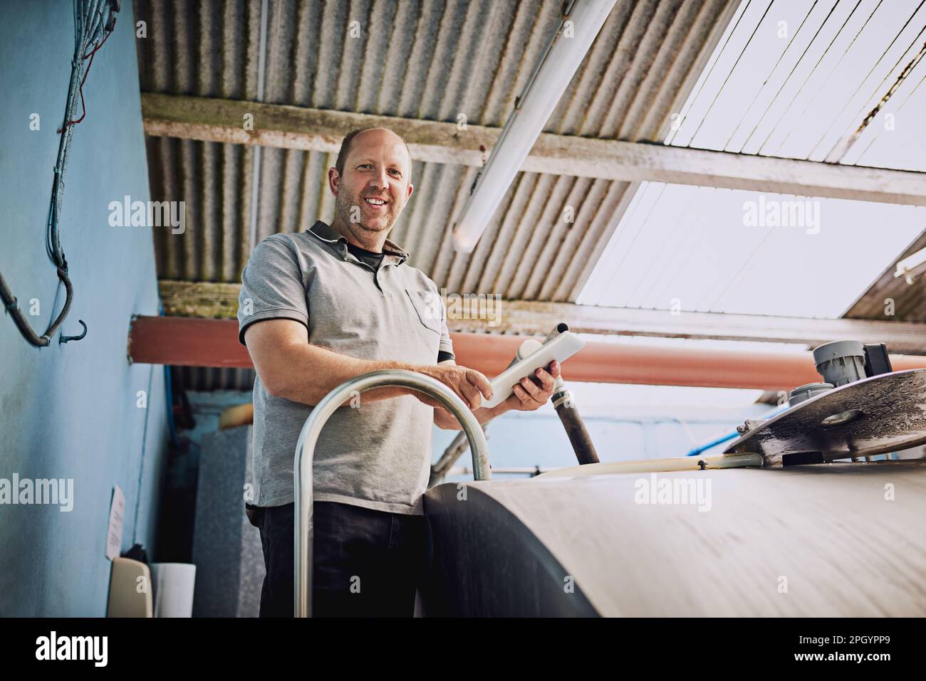 Assurez-vous que le lait est correctement traité. Portrait à angle bas d'un fermier mâle remplissant des récipients à lait dans son usine laitière. Banque D'Images