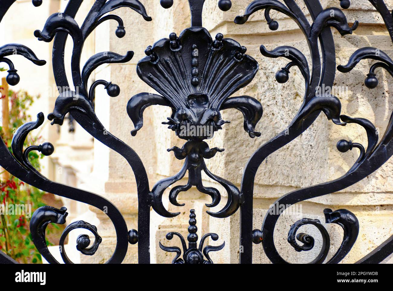 clôture en fer forgé noir au-dessus de la base et du seuil en pierre beige. éléments décoratifs en acier forgé entre les tiges verticales en acier. arrière-plan en pierre flou et doux. Banque D'Images