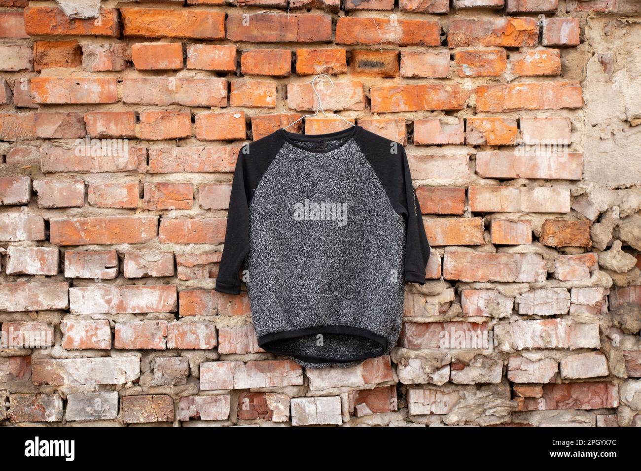 blouse pour femmes gris noir accrochée sur un vieux mur de briques à l'extérieur au soleil Banque D'Images