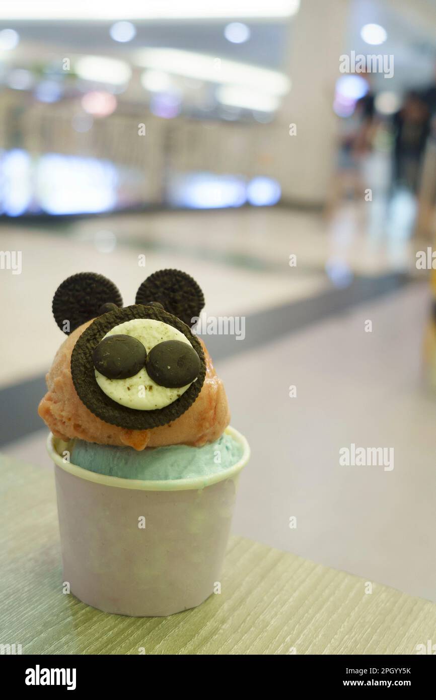 Une tasse de glace avec garniture de biscuit semblable à la souris servie sur la table en bois avec un arrière-plan flou. Banque D'Images