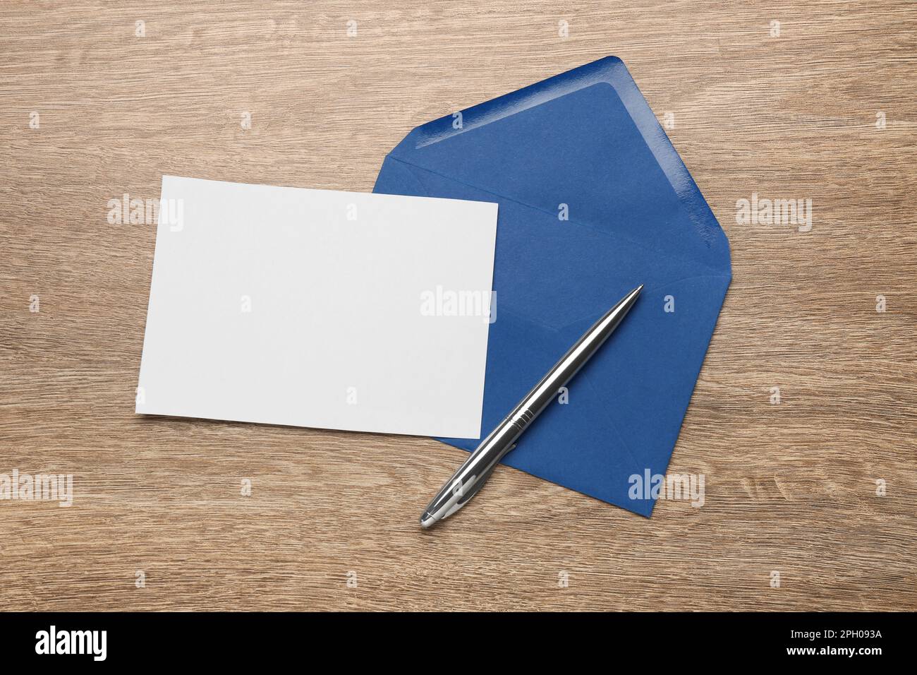 Enveloppe bleue avec lettre vierge et stylo sur table en bois, pose à plat Banque D'Images