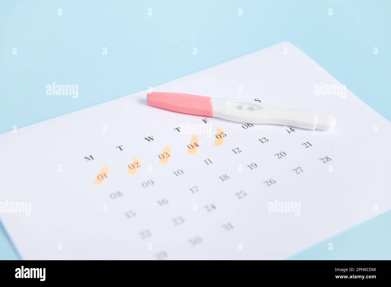 Test de grossesse et calendrier avec les dates des dernières règles  marquées sur fond bleu. Calcul de la date d'ovulation Photo Stock - Alamy
