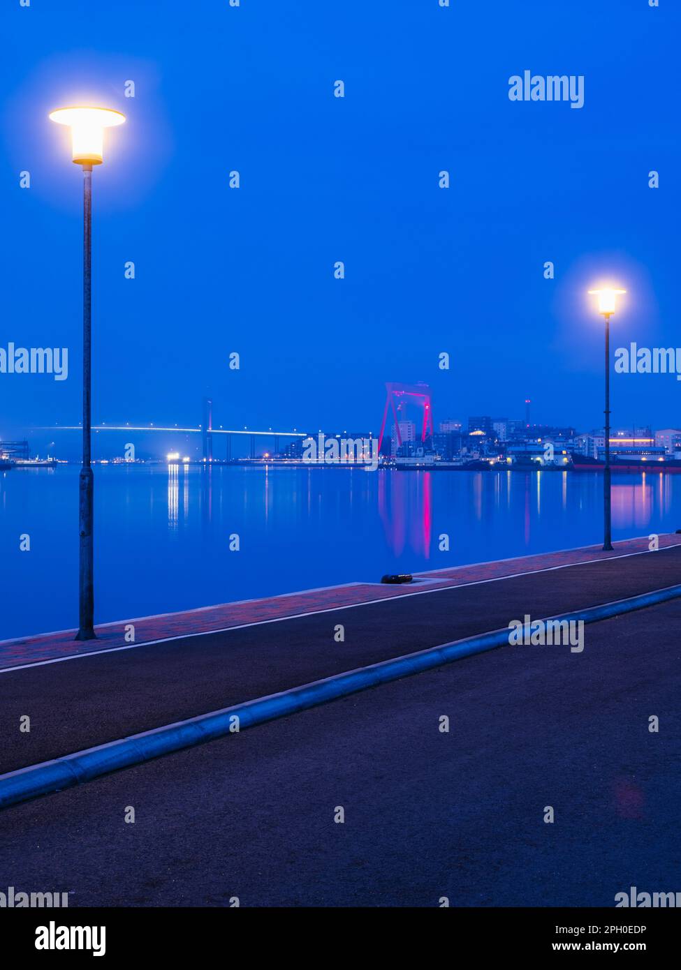 Des lampes lumineuses bordent l'horizon de Göteborg, en Suède, au crépuscule, créant un reflet sur son fleuve et éclairant les structures construites dans ce lit Banque D'Images