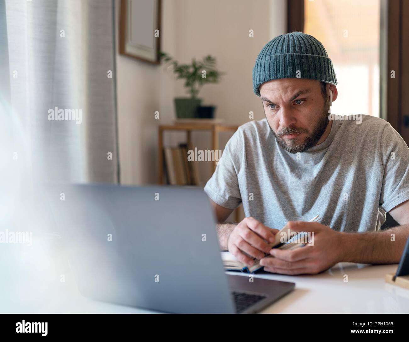 Homme adulte étudiant et enseignement à distance avec des manuels et des appareils d'information portables. Banque D'Images