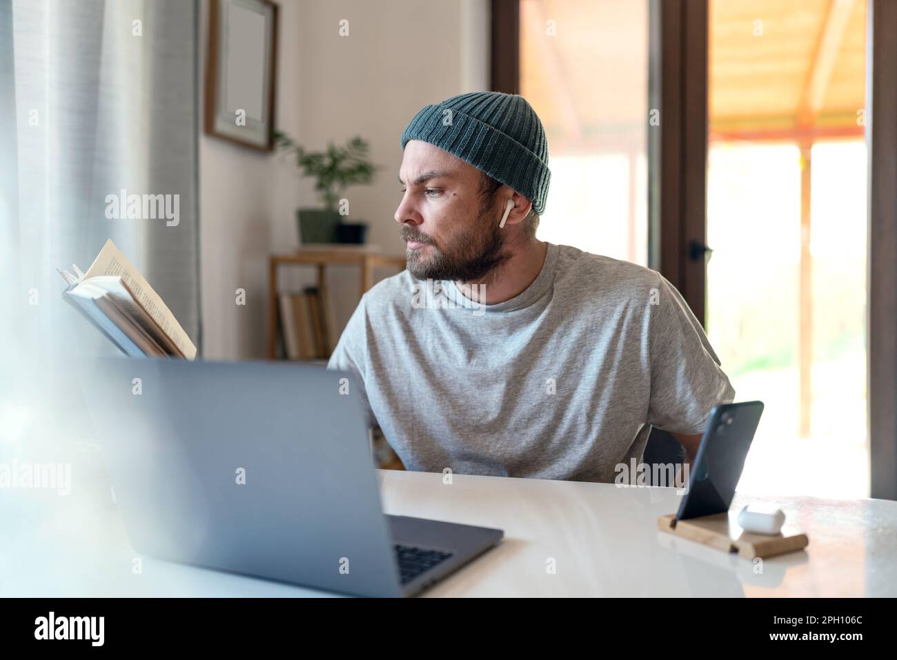 Homme adulte étudiant et enseignement à distance avec des manuels et des appareils d'information portables. Banque D'Images