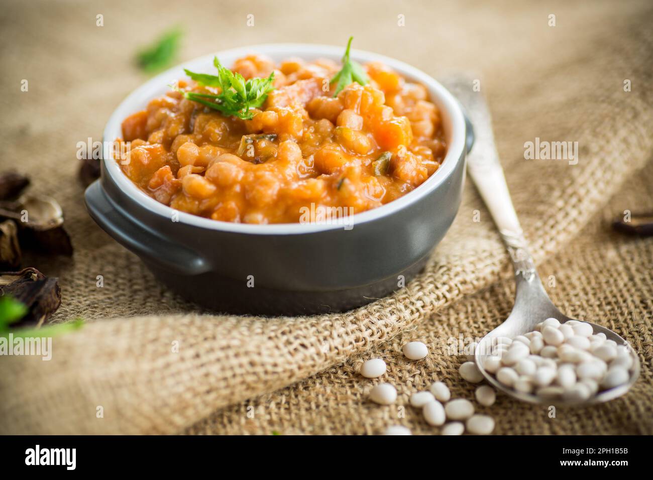 haricots cuits avec des légumes, des champignons et des épices, dans un bol, sur une table en bois. Banque D'Images