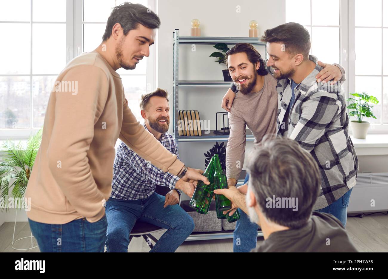 Groupe d'amis heureux de sexe masculin qui traînaient, boivent de la bière, se trinquer des bouteilles et s'amuser Banque D'Images