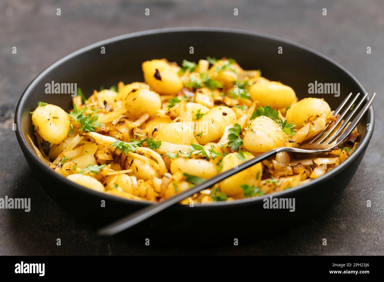 Gnocchi frit avec des choux hachés et des épices cajun. Banque D'Images