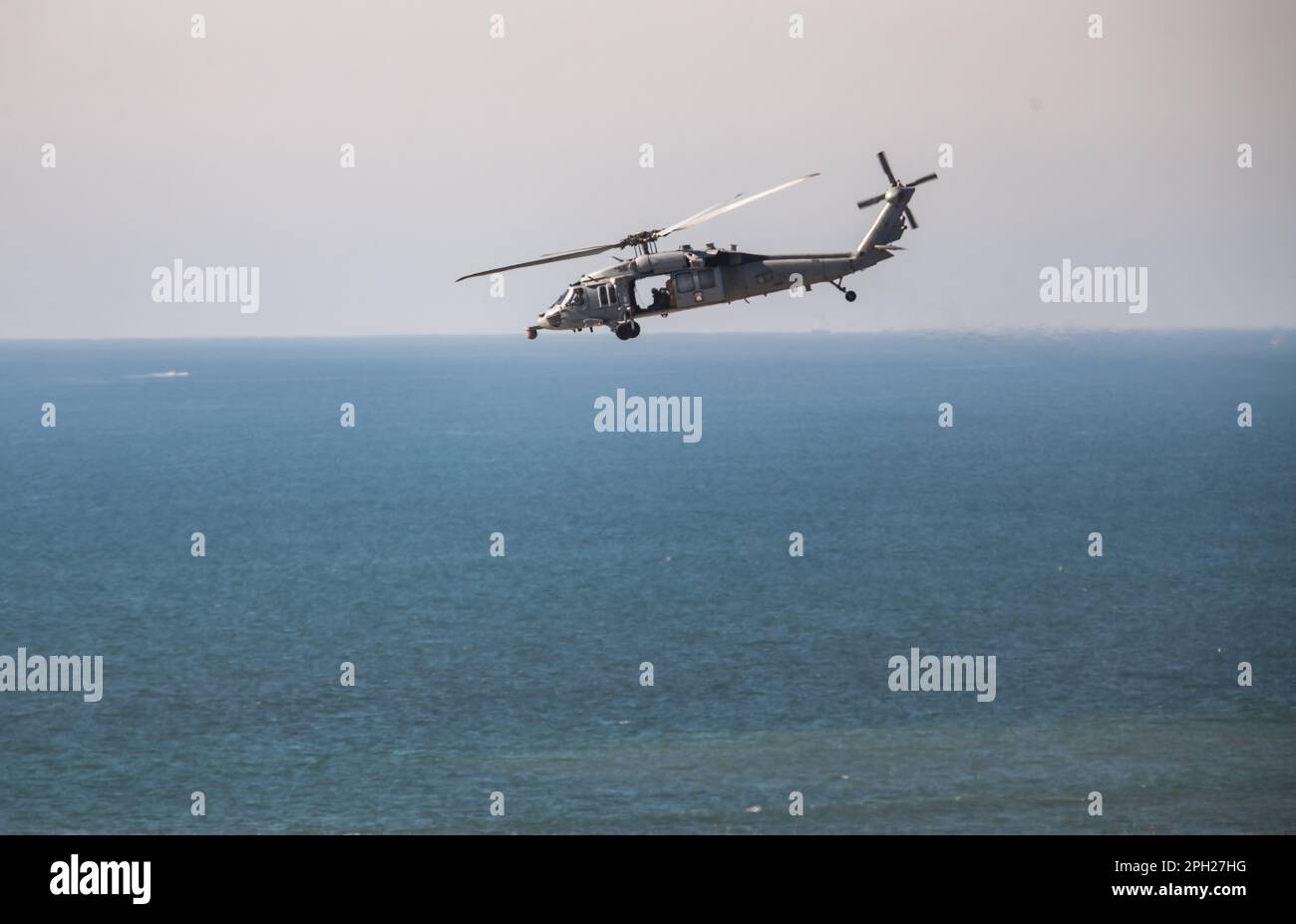 US Navy MH60S flotte entre un navire d'approvisionnement et le rivage par Camp Pendleton le long de la côte californienne. Banque D'Images