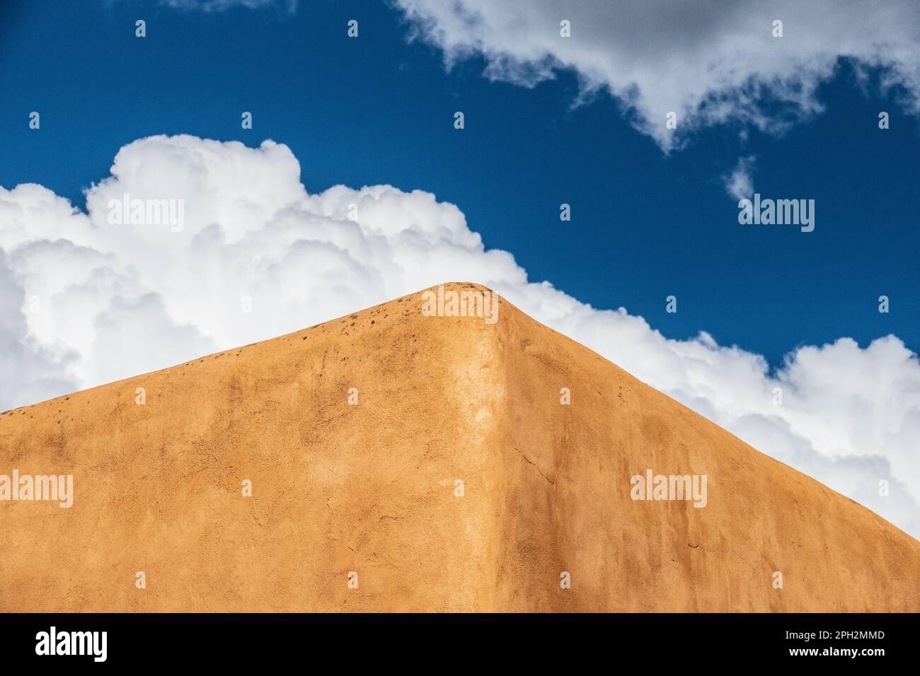 Murs recouverts d'Adobe d'un bâtiment à Taos Nouveau-Mexique en plan contre un ciel bleu avec des cumulus moelleux nuages Banque D'Images