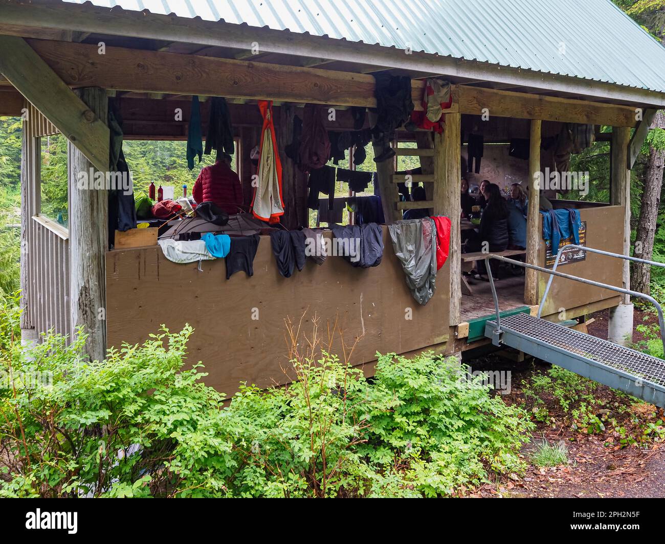 BC00713-00...C.-B. - les randonneurs qui tentent de sécher des vêtements et du matériel mouillés par temps de pluie à l'abri Elk Lake situé sur le sentier Sunshine Coast Trail. Banque D'Images