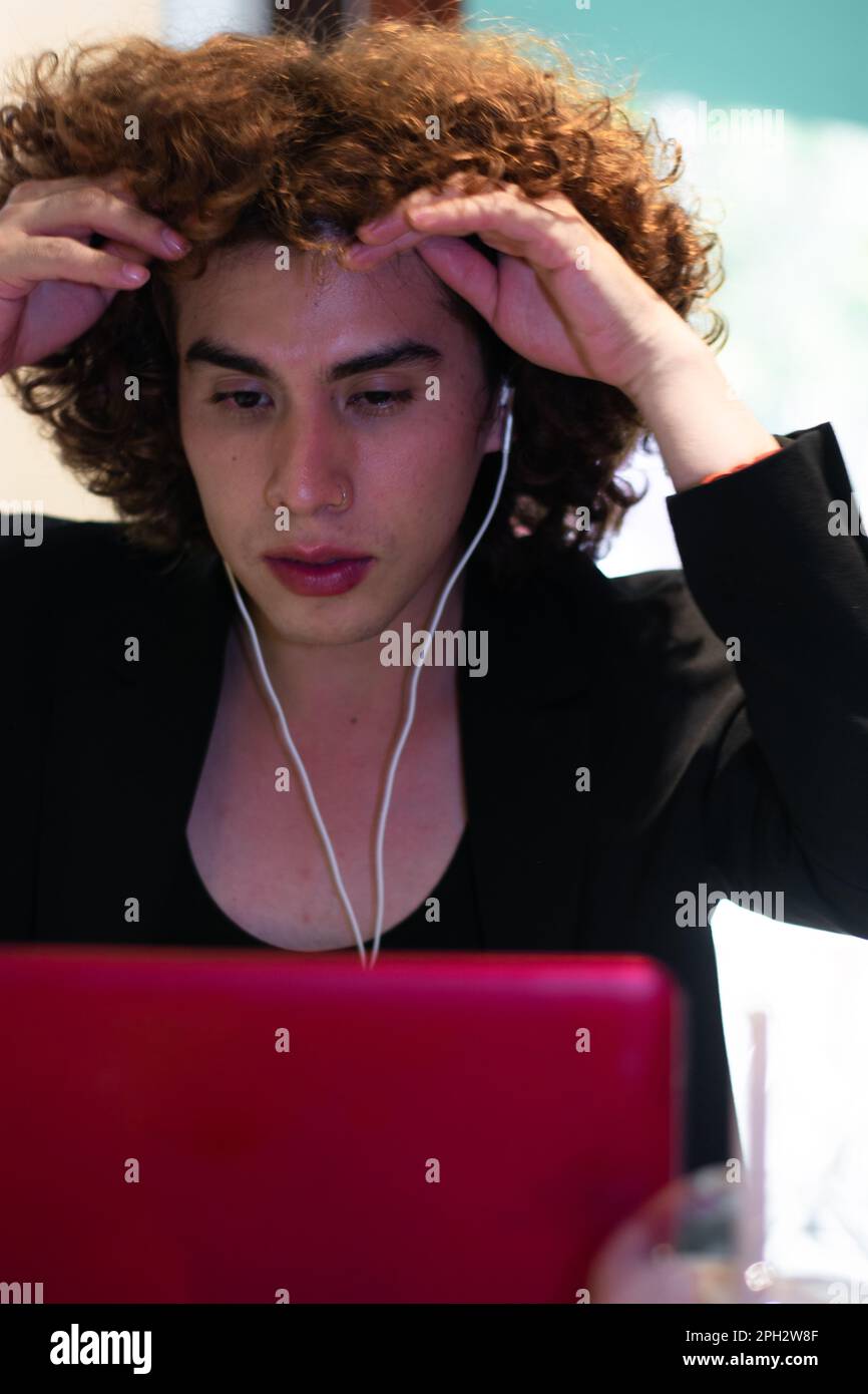 une personne non binaire montre une expression bouleversée devant un ordinateur portable pendant son travail Banque D'Images