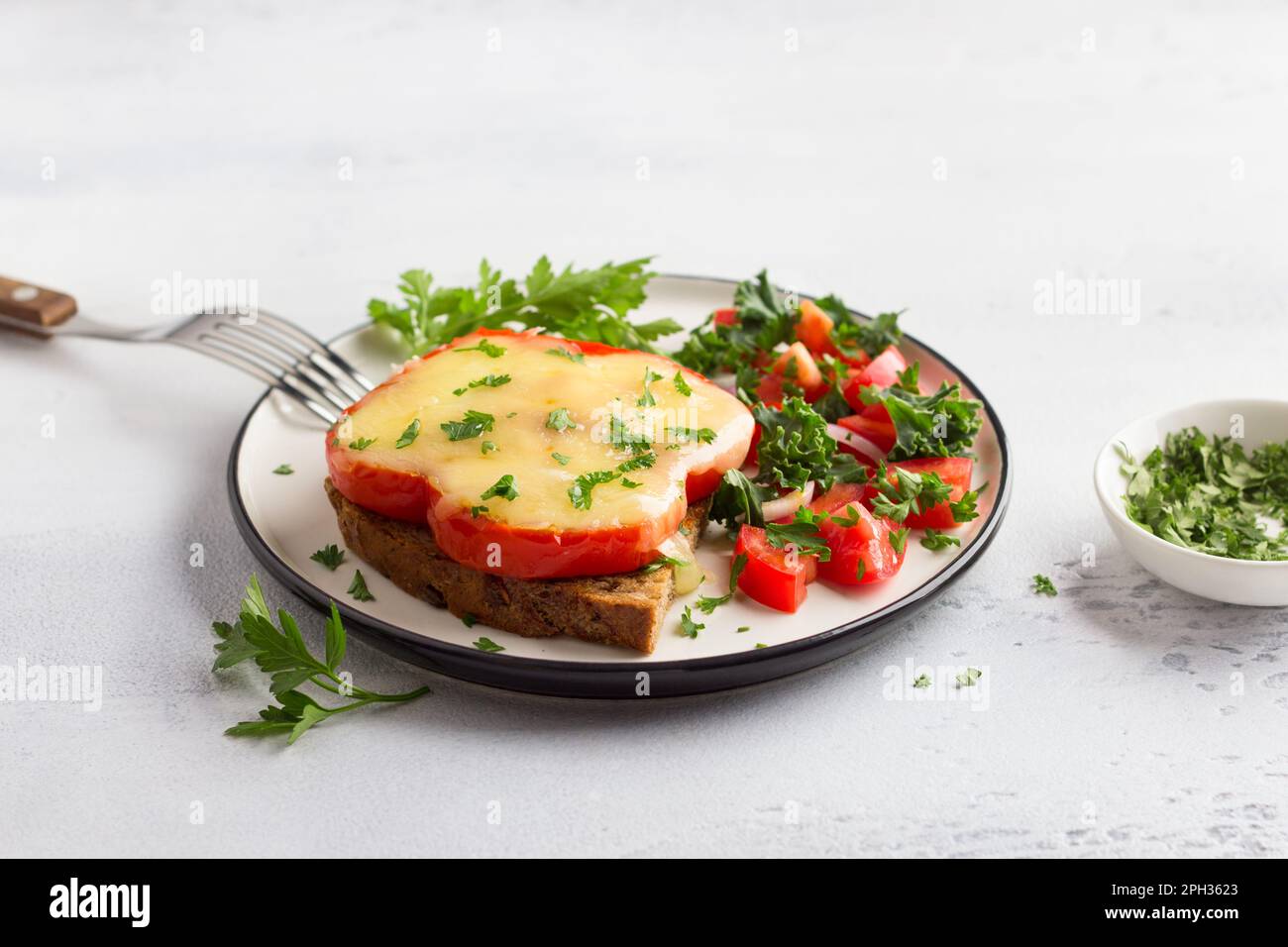 Délicieux petit déjeuner maison. Œufs frits au poivron rouge avec fromage, saupoudrés de persil haché avec de la tomate, de l'oignon rouge et de la salade verte sur un l Banque D'Images