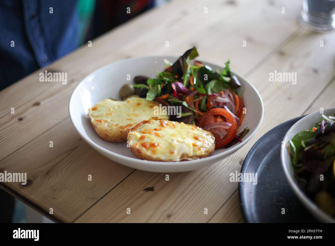 Pomme de terre cuite avec fromage fondu et salade d'accompagnement Banque D'Images